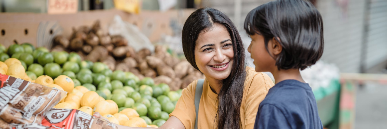 Mother and child in a grocery store at the produce section.